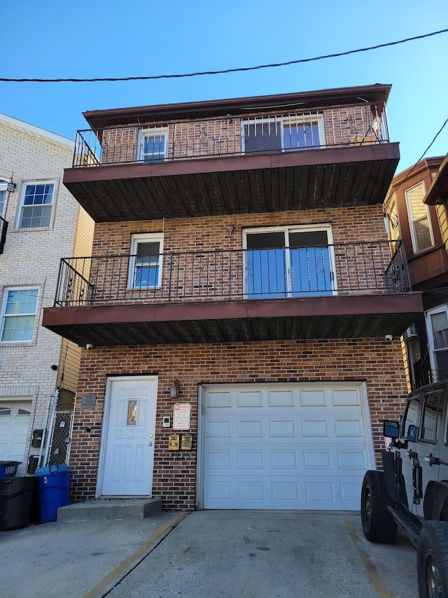 multi unit property with brick siding, an attached garage, and driveway