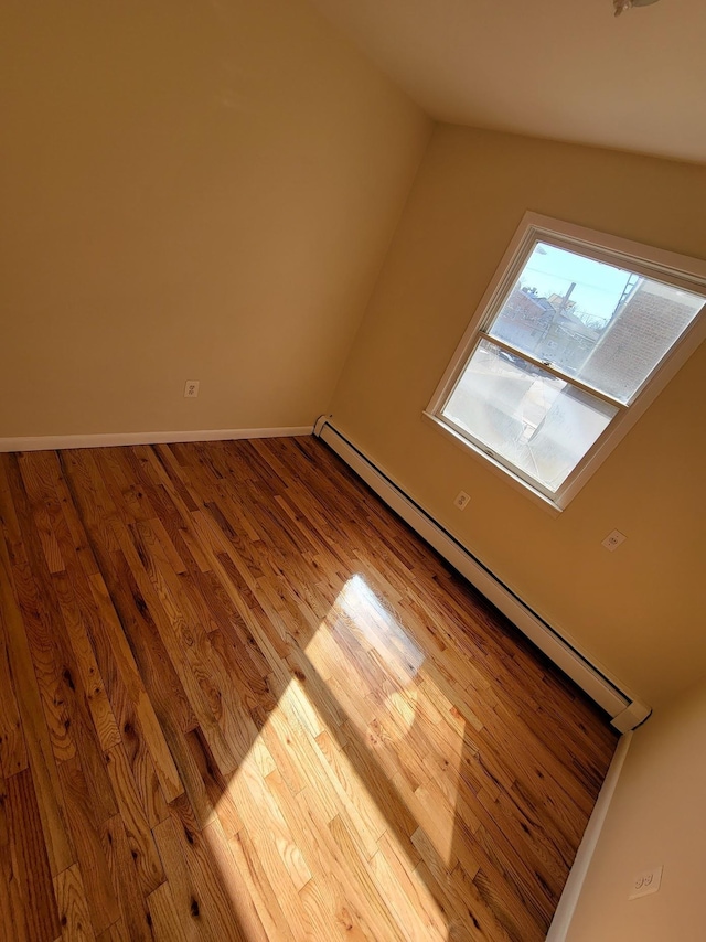 additional living space featuring wood finished floors, baseboards, and a baseboard radiator