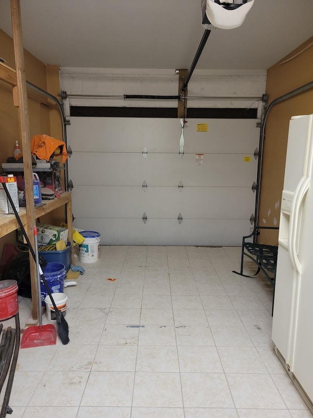 garage with a garage door opener and white fridge with ice dispenser