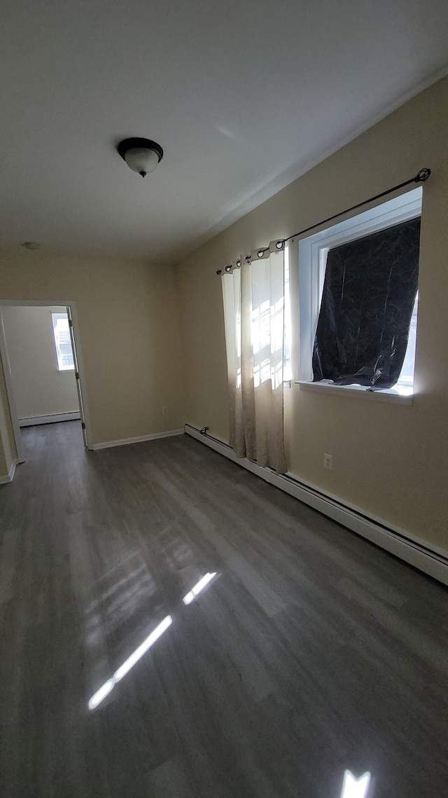 spare room with wood finished floors, baseboards, and a baseboard radiator