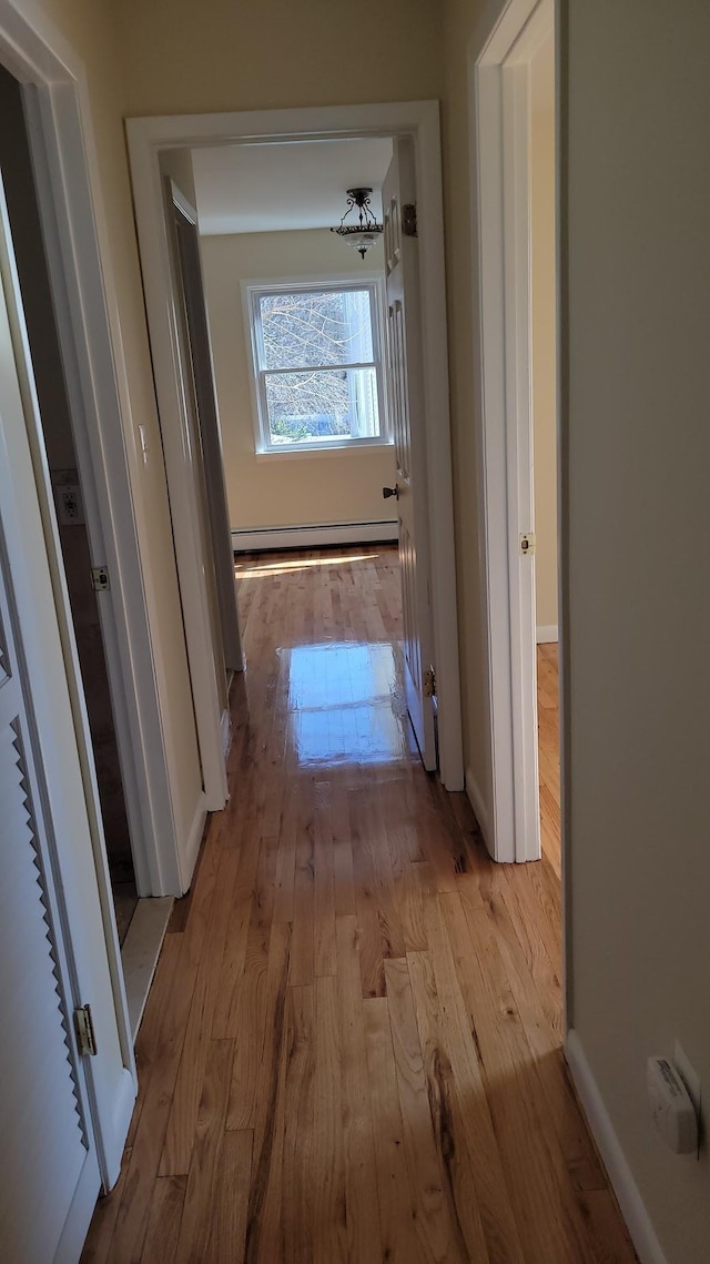 hall featuring hardwood / wood-style floors, baseboards, and baseboard heating