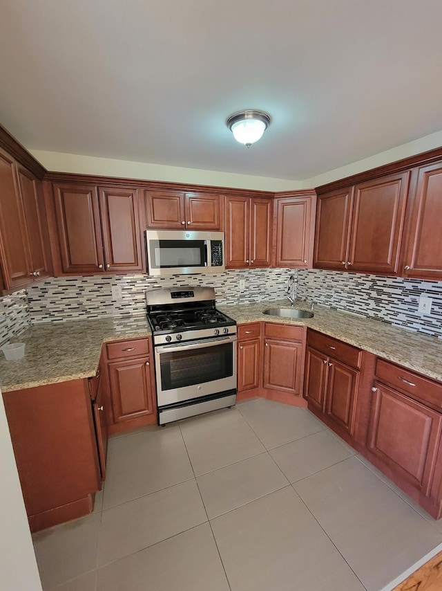 kitchen with tasteful backsplash, stainless steel appliances, light stone counters, and a sink