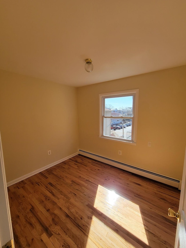 spare room featuring wood finished floors, baseboards, and baseboard heating