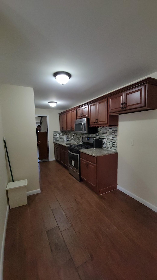 kitchen with decorative backsplash, baseboards, dark wood-style flooring, and appliances with stainless steel finishes