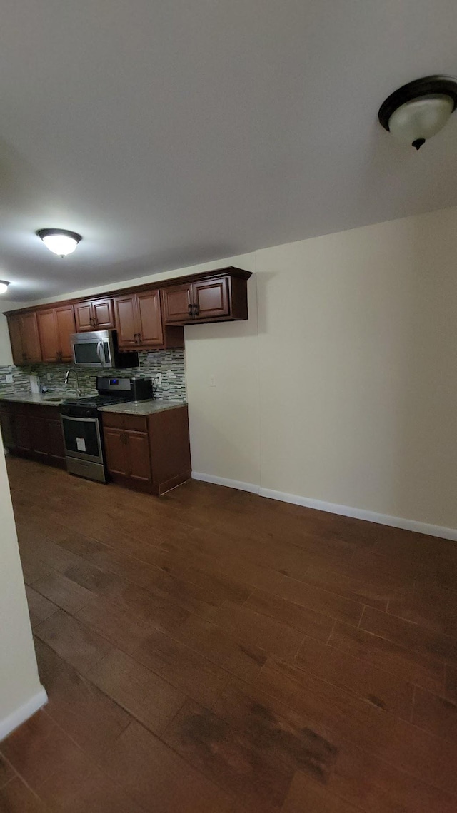 kitchen with stainless steel appliances, baseboards, dark wood-type flooring, and decorative backsplash