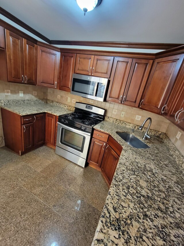 kitchen with a sink, tasteful backsplash, granite finish floor, stainless steel appliances, and crown molding