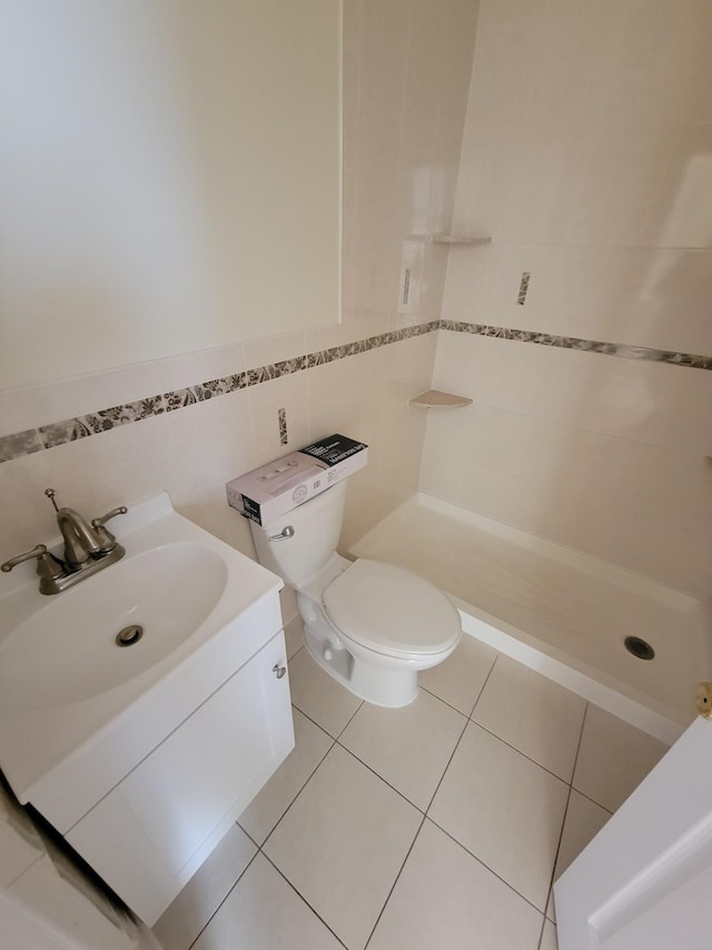 bathroom with vanity, tile patterned flooring, a shower stall, tile walls, and toilet