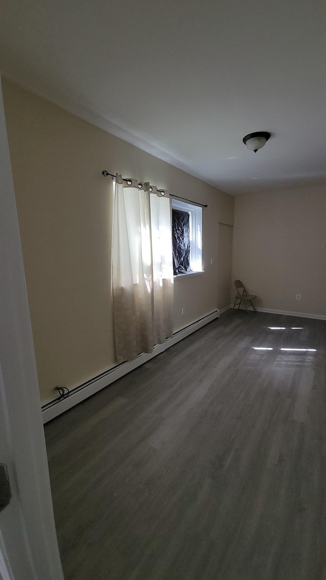 spare room with a baseboard radiator, baseboards, and wood finished floors