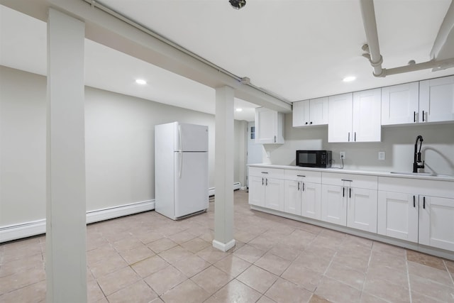 kitchen featuring white cabinets, freestanding refrigerator, light countertops, black microwave, and a sink