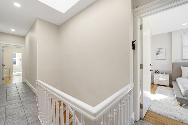 hallway with baseboards, a skylight, light tile patterned flooring, and recessed lighting