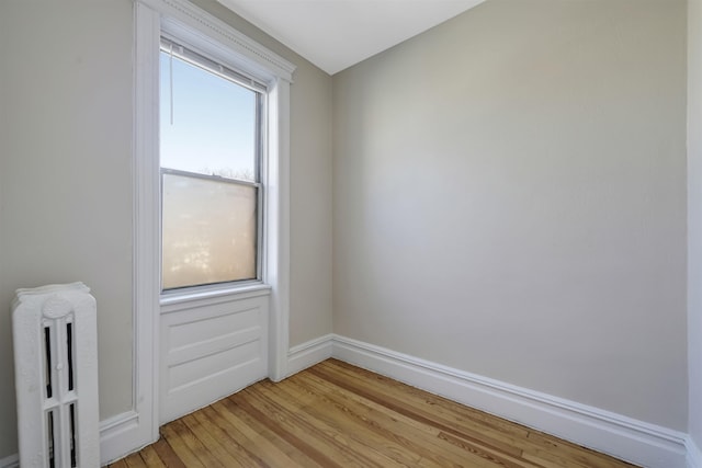 unfurnished room with light wood-style floors, radiator heating unit, and baseboards