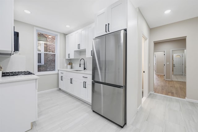 kitchen featuring baseboards, white cabinetry, appliances with stainless steel finishes, and a sink