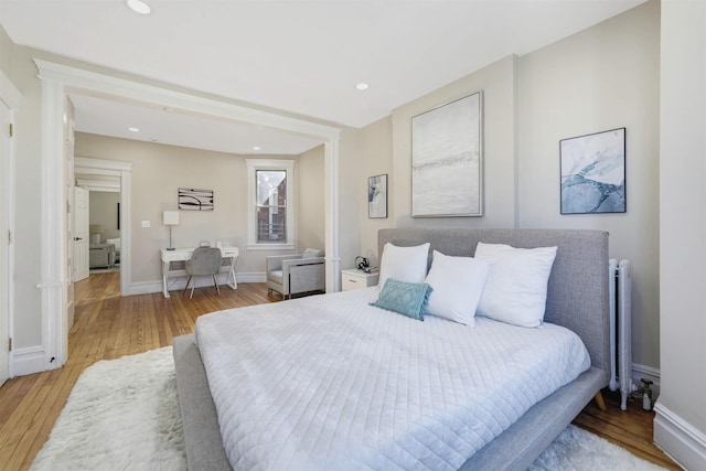 bedroom featuring recessed lighting, baseboards, radiator heating unit, and wood finished floors