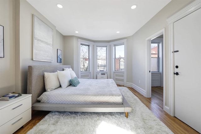 bedroom with baseboards, wood finished floors, and recessed lighting