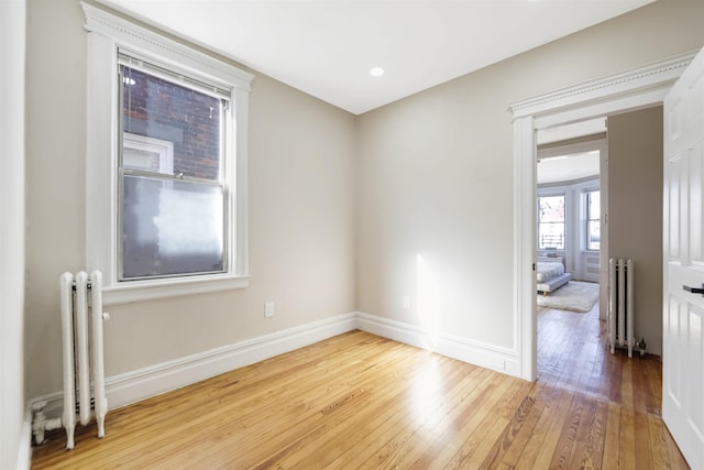 unfurnished room featuring radiator, baseboards, and wood finished floors