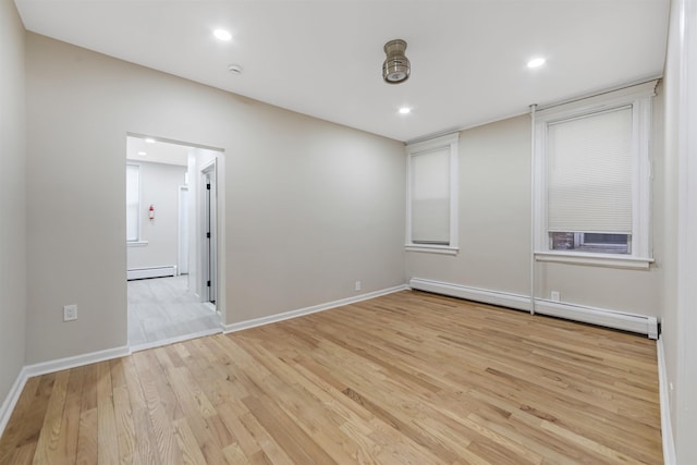 empty room featuring a baseboard radiator, light wood-style flooring, and recessed lighting