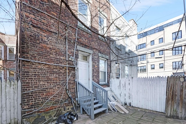 property entrance featuring fence and brick siding