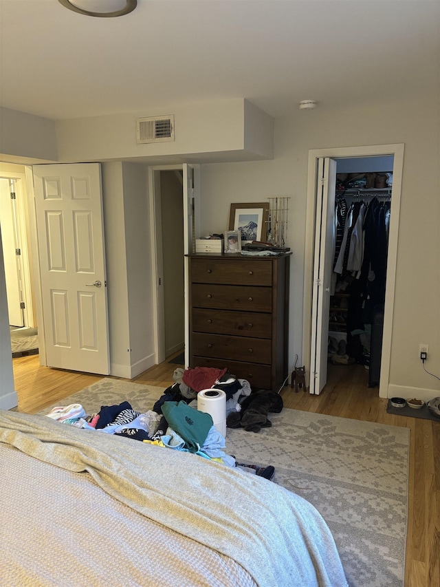 bedroom with a walk in closet, light hardwood / wood-style floors, and a closet