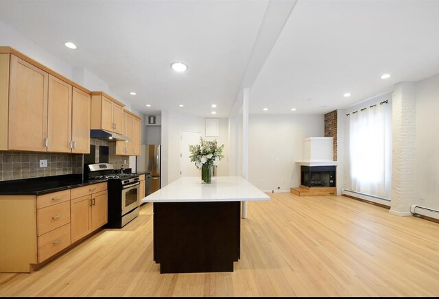 kitchen with light hardwood / wood-style flooring, beamed ceiling, a kitchen island, dark brown cabinetry, and brick wall