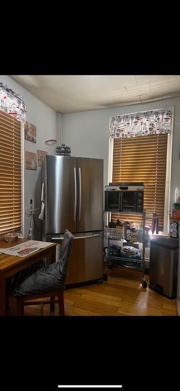 interior space featuring wood-type flooring and stainless steel refrigerator