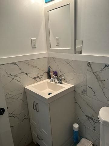 bathroom with tile walls, vanity, and toilet