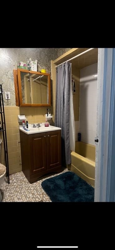 bathroom featuring tile walls, vanity, and shower / bath combo with shower curtain