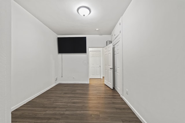 unfurnished bedroom featuring dark wood finished floors, baseboards, and a closet