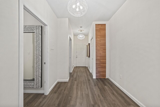 hall with baseboards, dark wood finished floors, and a chandelier