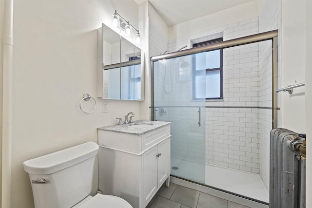 bathroom with radiator, a shower stall, vanity, tile patterned floors, and toilet
