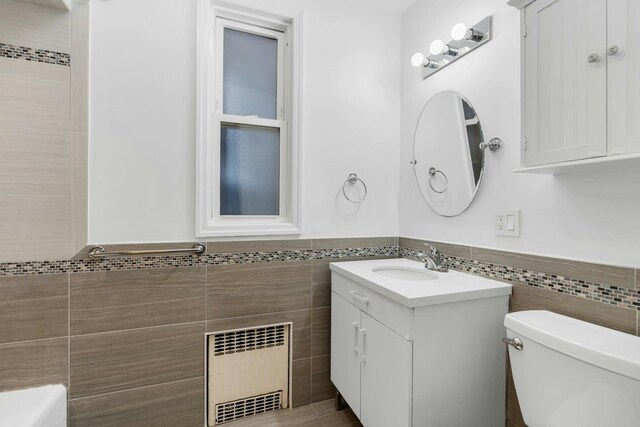 123 Shippen St, Weehawken, NJ 07086 - bathroom with tile walls, radiator heating unit, vanity, and wainscoting