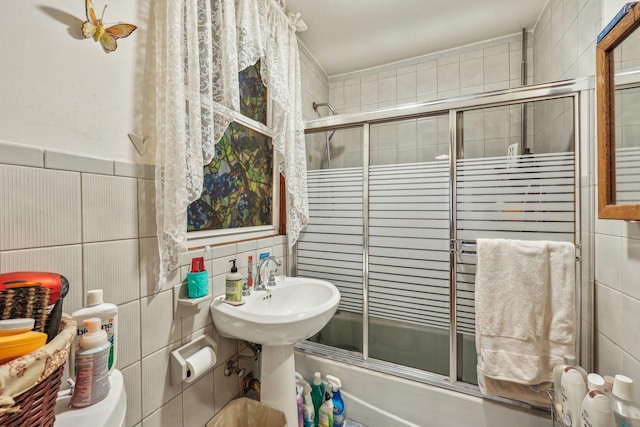 full bath featuring bath / shower combo with glass door and tile walls