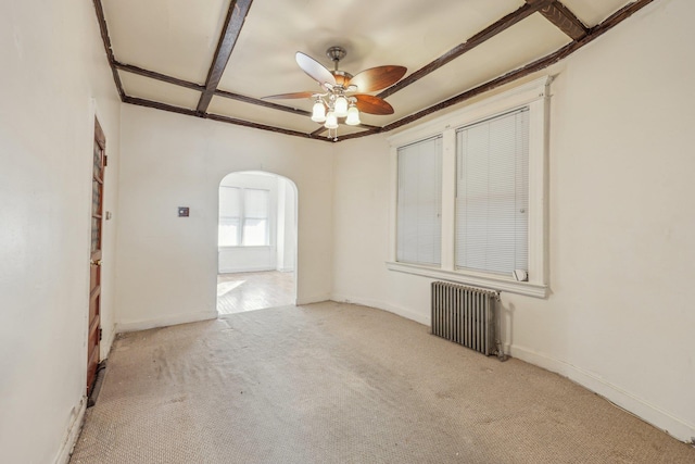 carpeted spare room with ceiling fan, baseboards, radiator heating unit, arched walkways, and coffered ceiling