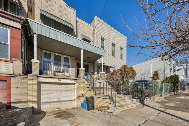 view of property with stairs, fence, a garage, and driveway