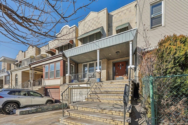 townhome / multi-family property featuring brick siding, driveway, and a porch