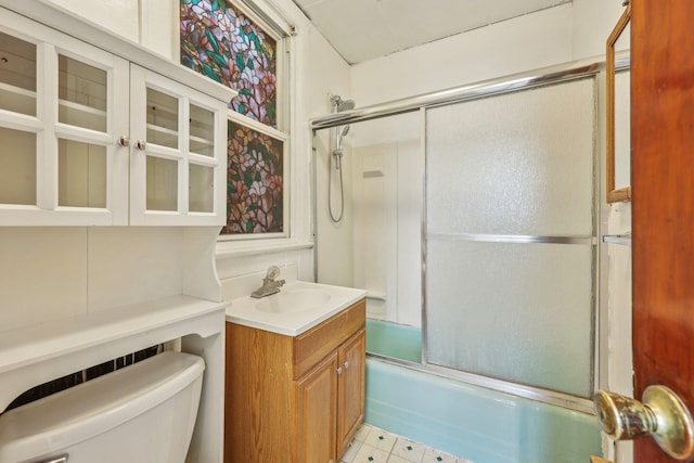 full bathroom with combined bath / shower with glass door, toilet, vanity, and tile patterned floors