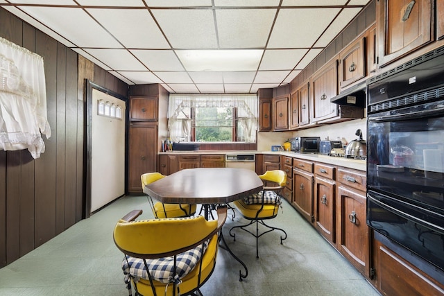81 Atlantic St, Jersey City, NJ 07304 - kitchen with black oven, a warming drawer, wooden walls, light countertops, and a drop ceiling