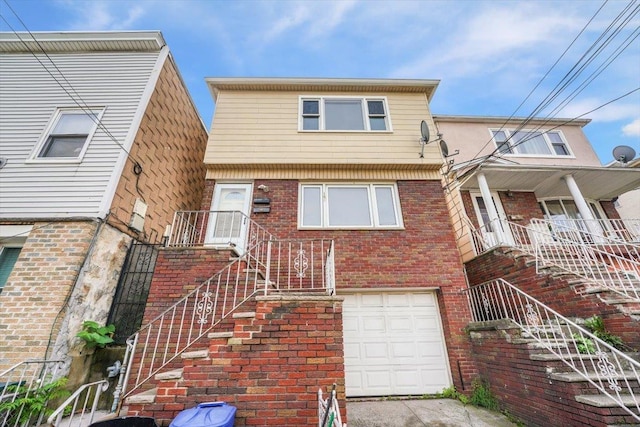 view of property with a garage, brick siding, and stairway