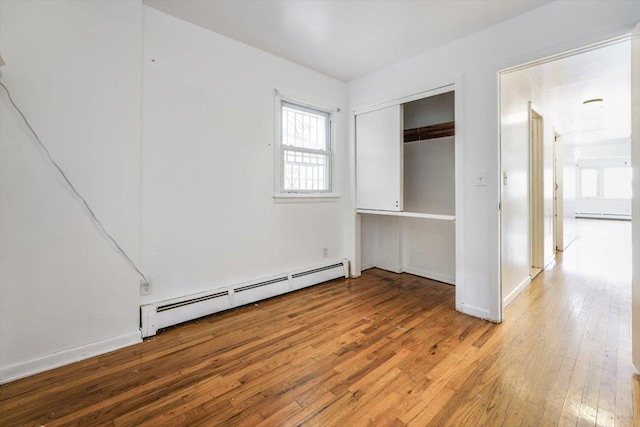 spare room with a baseboard heating unit, light wood-type flooring, a baseboard radiator, and baseboards