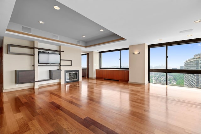 200 Old Palisade Rd Ph 4/5, Fort Lee, NJ 07024 - unfurnished living room featuring a wall of windows, wood finished floors, a glass covered fireplace, a raised ceiling, and recessed lighting