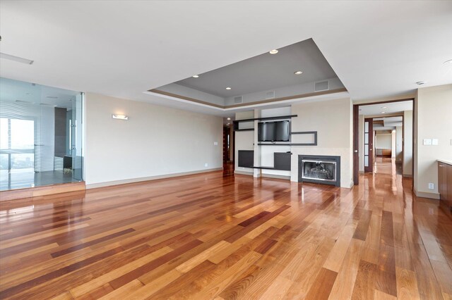 200 Old Palisade Rd Ph 4/5, Fort Lee, NJ 07024 - unfurnished living room featuring a glass covered fireplace, light wood-type flooring, and a tray ceiling