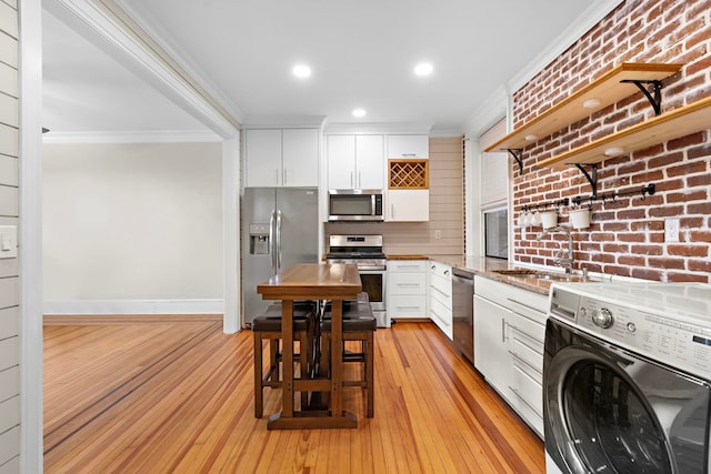 kitchen featuring stainless steel appliances, washer / dryer, sink, and white cabinets