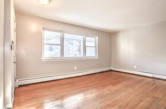 spare room with a baseboard heating unit and wood-type flooring