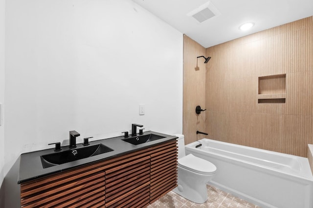 full bathroom featuring vanity, tiled shower / bath combo, and toilet