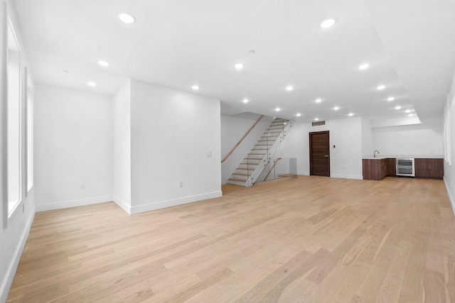 basement with sink, beverage cooler, and light hardwood / wood-style flooring