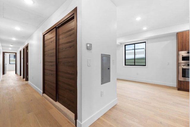 hall with light hardwood / wood-style flooring and electric panel