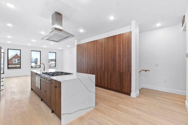 kitchen with stainless steel appliances, island exhaust hood, a large island, and light hardwood / wood-style flooring