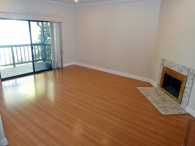 unfurnished living room with a premium fireplace, hardwood / wood-style flooring, and crown molding