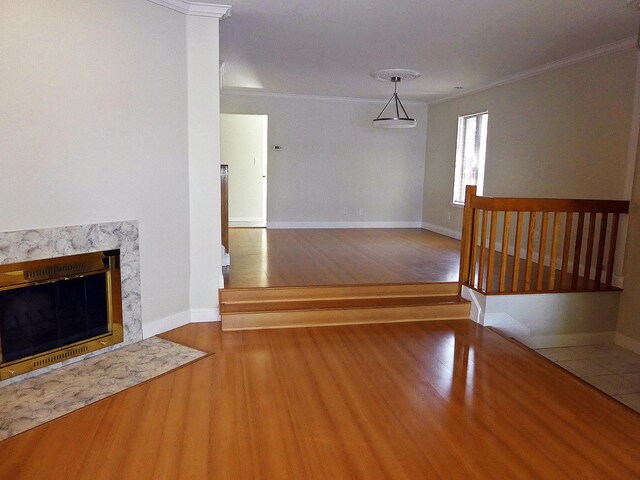 unfurnished living room featuring wood-type flooring, a high end fireplace, and ornamental molding