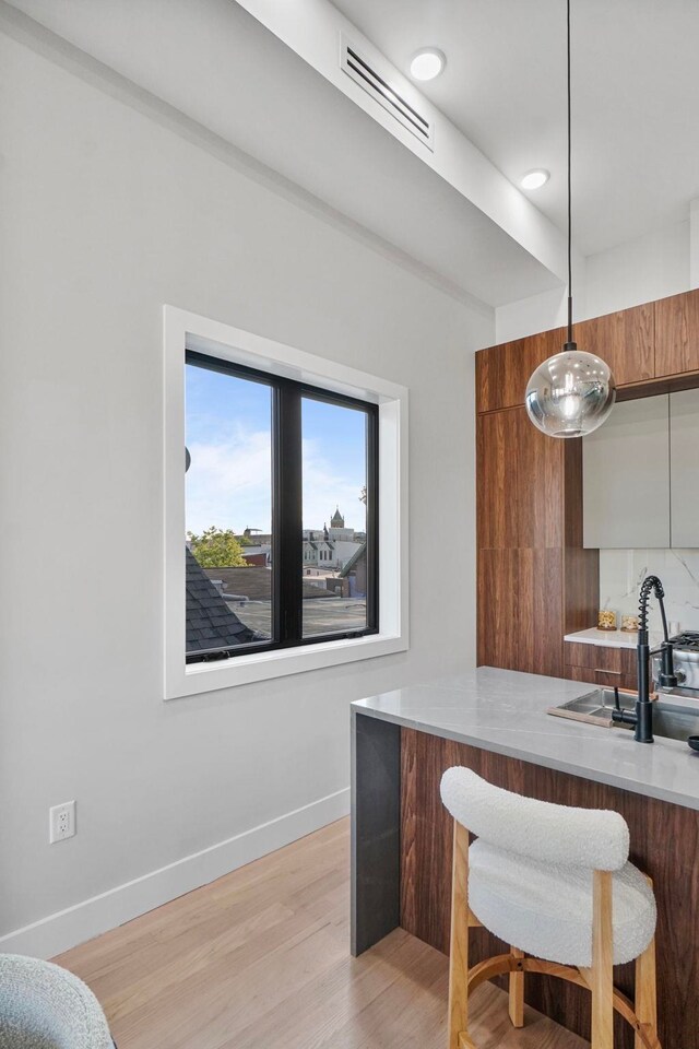 371 New York Ave Unit 2, Jersey City, NJ 07307 - kitchen featuring modern cabinets, hanging light fixtures, a breakfast bar, light wood finished floors, and brown cabinets