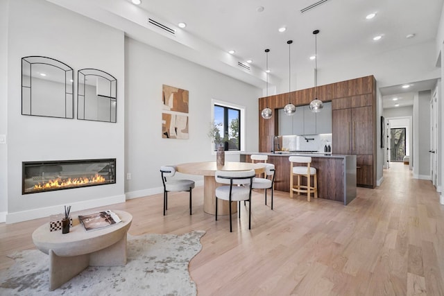 371 New York Ave Unit 2, Jersey City, NJ 07307 - dining space featuring recessed lighting, light wood-style floors, a glass covered fireplace, and a towering ceiling